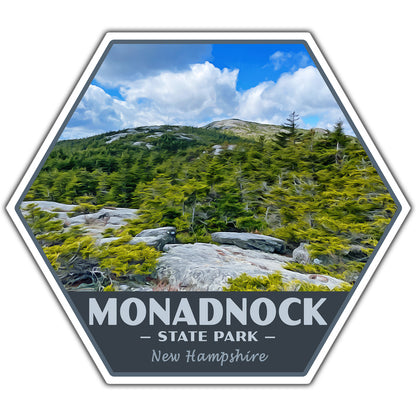 A hexagonal sticker or patch design featuring a scenic photograph of Monadnock State Park in New Hampshire, with a dark gray bottom banner reading 'MONADNOCK STATE PARK New Hampshire' in white text.